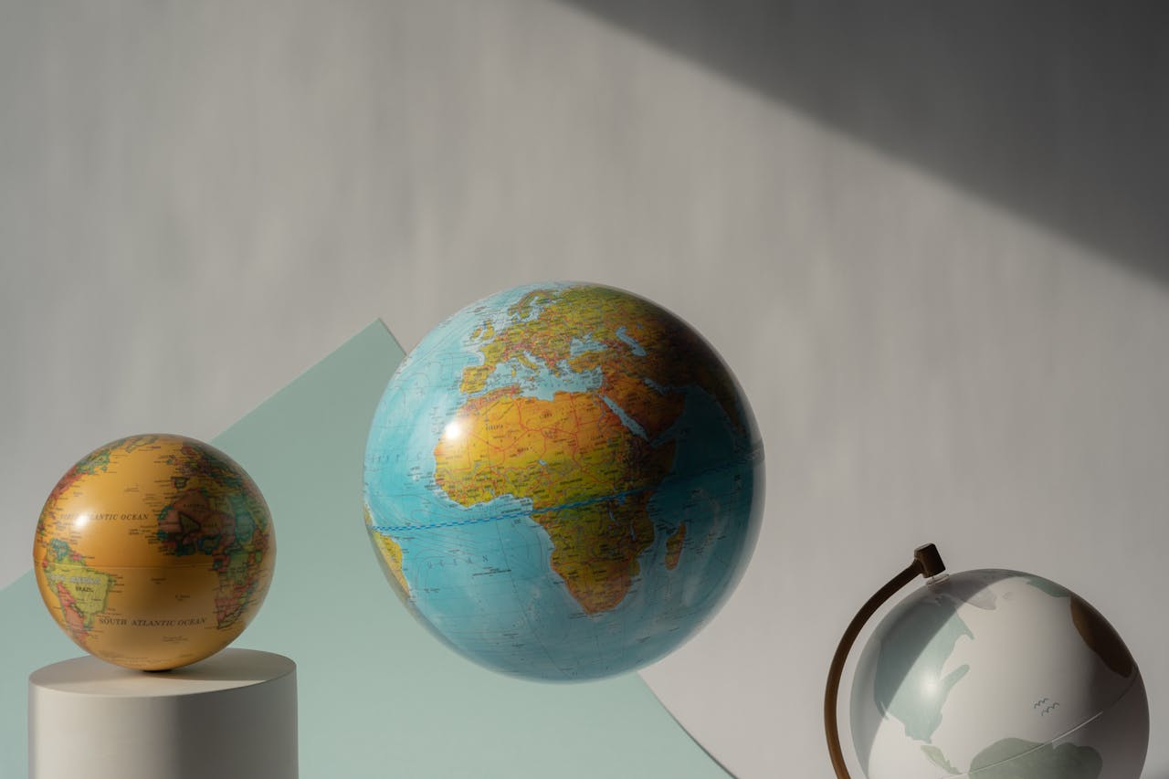 services-04 Three globes floating in a studio setting, showcasing maps of the world.